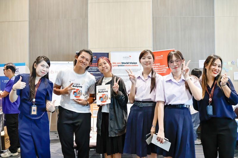 เยาวชนและเจ้าหน้าที่ศุภนิมิตฯ ถือหนังสือ Cyber Bullying หน้าบูธมูลนิธิศุภนิมิตแห่งประเทศไทย